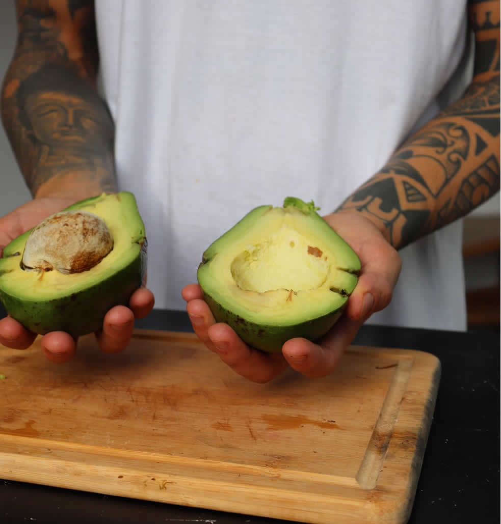 Homem segurando um avocado em suas mãos